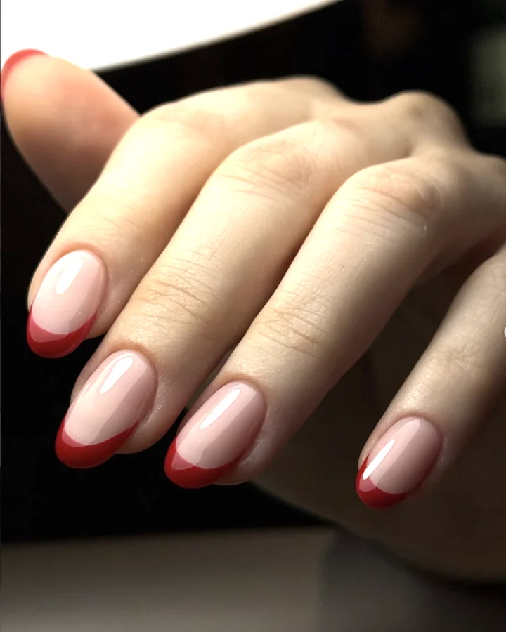 French rouge sur des ongles amande, sur fond sombre
